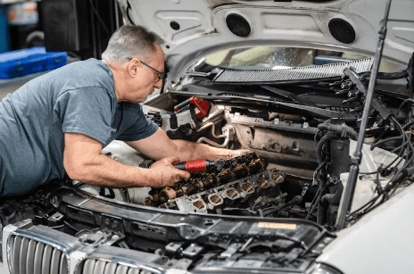 Mechanic performing engine diagnostics and repair inside the vehicle at German Auto Repair LLC workshop in Rockville
